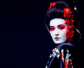 Wall Mural - young pretty real geisha in kimono with sakura and decoration on black background