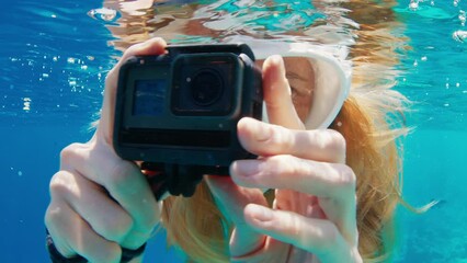 Sticker - Woman with mask swims underwater with action camera and films a content