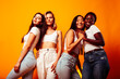 © iordani - diverse multi nation girls group, teenage friends company cheerful having fun, happy smiling, cute posing on yellow background, lifestyle people concept, african-american, asian and caucasian