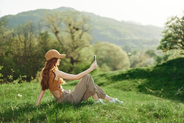 Bottom view young student freelancer woman in green jacket jeans sit on bench in spring park outdoors talk by mobile cell phone look aside. People urban lifestyle concept