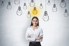 Creative Idea And Startup Concept With Happy And Smiling Young Woman In White Shirt At Light Wall Background With Hand Drawn White Lightbulbs And Yellow One Switched On