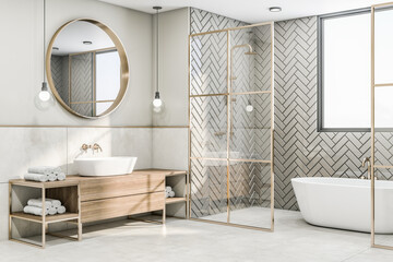 Perspective view on sunny modern interior design bathroom with herringbone ceramic tales bath zone, wooden sink cabinet under round mirror and glass partitions with gold decorations. 3D rendering