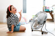 © ADDICTIVE STOCK - Little girl at home sitting on the floor playing with fan