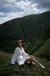 © Alex - Brunette girl in white on the background of the green mountains.