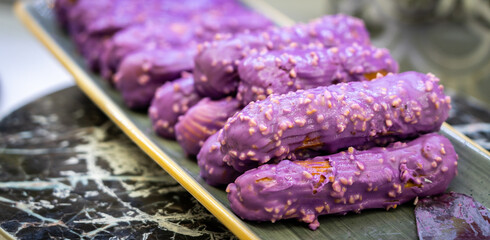 Wall Mural - Eclairs with sweet purple topping with nuts on serving plate