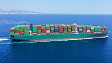 Aerial Drone Photo Of Huge Container Tanker Ship Carrying Truck Size Colourful Containers In Deep Blue Open Ocean Sea
