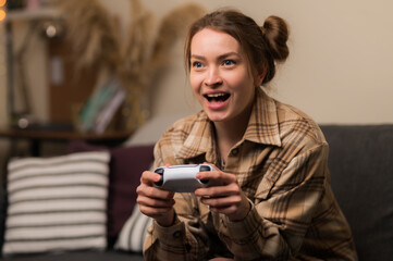 Wall Mural - A girl with a gamepad plays a video game online with friends. Rejoices to win, emotionally reacts. Communications, new digital technologies, youth culture, competitions, tournaments, battles.