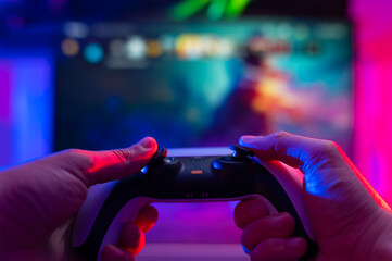 Close-up. Modern gamepad. A gamer plays video games on a technological background on a TV screen. Virtual reality, entertainment, communications, cyberspace.