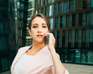 Executive working with a mobile phone in the street with office buildings in the background