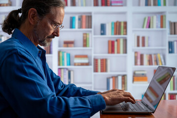 Concentrated serious businessman thinking of problem solution working on laptop. Thoughtful male programmer market analyst or software developer considering risks using computer sitting at workplace.