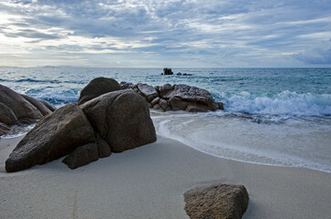 Wall Mural - Beautiful rocks on sand beach and white waves of water in the sea
