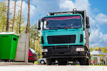 Fototapete - A garbage truck picks up garbage in a residential area. Loading mussar in containers into the car. Separate collection and disposal of garbage. Garbage collection vehicle.