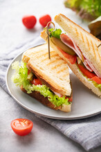 Club Sandwich On A Plate Of Ham Cheese, Cucumber, Tomato And Lettuce Leaves Close-up On A Blue  Background With Mayonnaise
