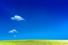 白い雲の浮かぶ青空を背景にした広大な緑の丘。背景素材