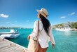 © Syda Productions - people, summer holidays and leisure concept - happy young woman in white shirt and straw hat with bag over pier and boat or tropical sea background in french polynesia