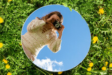Photography And Nature Concept - Woman With Camera And Sky Reflection In Round Mirror On Grass
