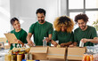 © Syda Productions - charity, donation and volunteering concept - international group of happy smiling volunteers packing food in boxes according to list on clipboard at distribution or refugee assistance center