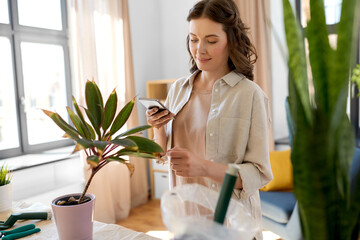 Poster - people, gardening and housework concept - happy woman with smartphone and pot flower at home