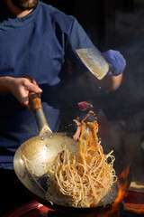 Chef cooks Chinese noodle wok at street food festival