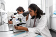 science research, work and people concept - international team of scientists with microscopes working in laboratory