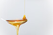 close up of honey being poured into a silver spoon, honey is a natural sweetener as a substitute for sugar