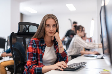 Casual business woman working on desktop computer in modern open plan startup office interior. Selective focus 
