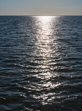 Glittering Of Evening Sunlight Reflects On Sea Surface. Sparkling Sunlight Over Sea Surface On Waves. Sparkling Water Background.