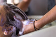 Closeup of hairdresser's hands washing hair of a woman in hair salon.