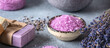 Lavender spa products. Lavender sea salt , lavender flowers and lavender soap. Gray rustic background. Side view, selective focus. Banner