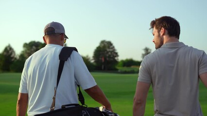 Wall Mural - Dad son going fairway course. Two golfers take sport equipment clubs outdoors.