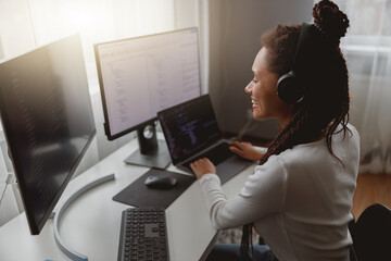Wall Mural - close up of smiling mixed-race woman web expert programming on computer looking at monitors
