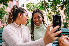 Happy Diverse Girlfriends Taking Selfie On Bench