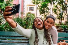 Happy Diverse Girlfriends Taking Selfie On Bench
