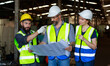 © atitaph - Male and female engineers chat with factory workers as they use machine drawings, planning for industrial maintenance