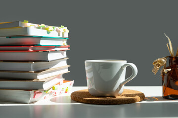 Sticker - a stack of books with a mug of tea on a white table.