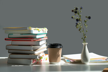 Sticker - a stack of books on a table with a glass of coffee and a vase of dried flowers.