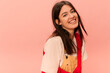 © Look! - Cute young caucasian girl with dark hair smiles with her teeth at camera on pink background. Brunette girl wears casual spring clothes. Lifestyle, different emotions, leisure concept.