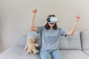 asian oman playing a video game with  VR glasses at home