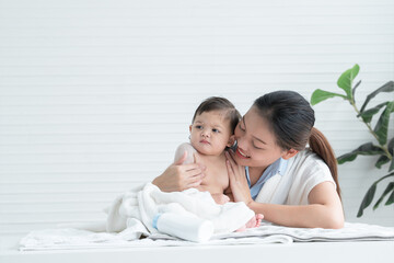 cute caucasian little naked toddler baby girl sitting on towel after bathing and wipe body dry while