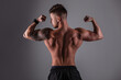 © alones - Sporty handsome bodybuilder guy with muscular rear and back poses and shows muscle against a dark background in the studio