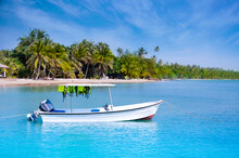 Small White Boat With Green Life Jacket Floating In A Beautiful Beach