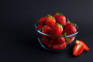 Wall Mural - Strawberry in the glass  bowl on the black background. Copy space.Closeup.