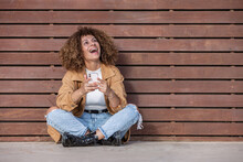 Hispanic Woman With Mobile Phone Laughing Out Loud