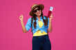 © khmelev - Happy girl with tickets on isolated pink background. Traveler holding passport. Smiling student wearing casual clothes. Tourism concept