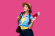 © khmelev - Smiling caucasian woman student holding passport and plane tickets. Girl in casual clothes and straw hat. Female traveler on pink isolated background.