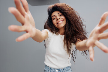 Young smiling cheerful friendly caucasian nice curly woman 20s afro long hair in casual white shirt stretch hands isolated on pastel gray color background studio portrait. Wide Angle View, Copy Space