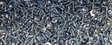 A Many New Short Grey Shiny Self-tapping Screws With Cross Heads. Galvanized Construction Fasteners. Industrial Wide Texture Background.