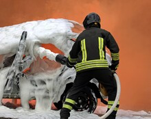 Firefighter Exercise Extinguishing The Car Fire By Spreading The Foam With The Hose