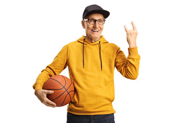 Sticker - Cheerful elderly man holding a basketball and gesturing rock and roll sign