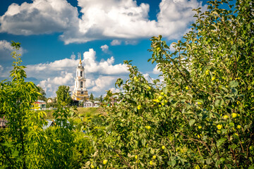 View of ancient russian architecture, churches and Kremlin on the bank of river Kamenka in Suzdal. Summer landscape of orthodox churches on sunset, blue sky with cumulus clouds. Golden Ring of Russia.